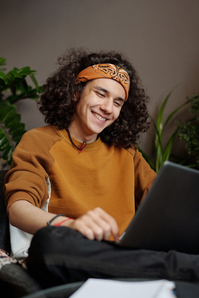 Young Man Sits at His Laptop and Smiles